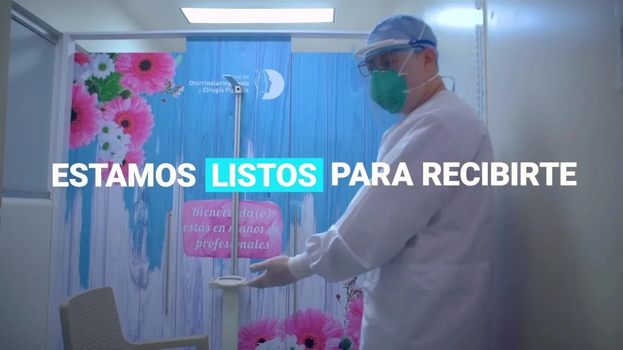 Miniatura del video «Estamos listos para recibirte»: un profesional con el equipo de bioseguridad puesto, en una sala con flores
